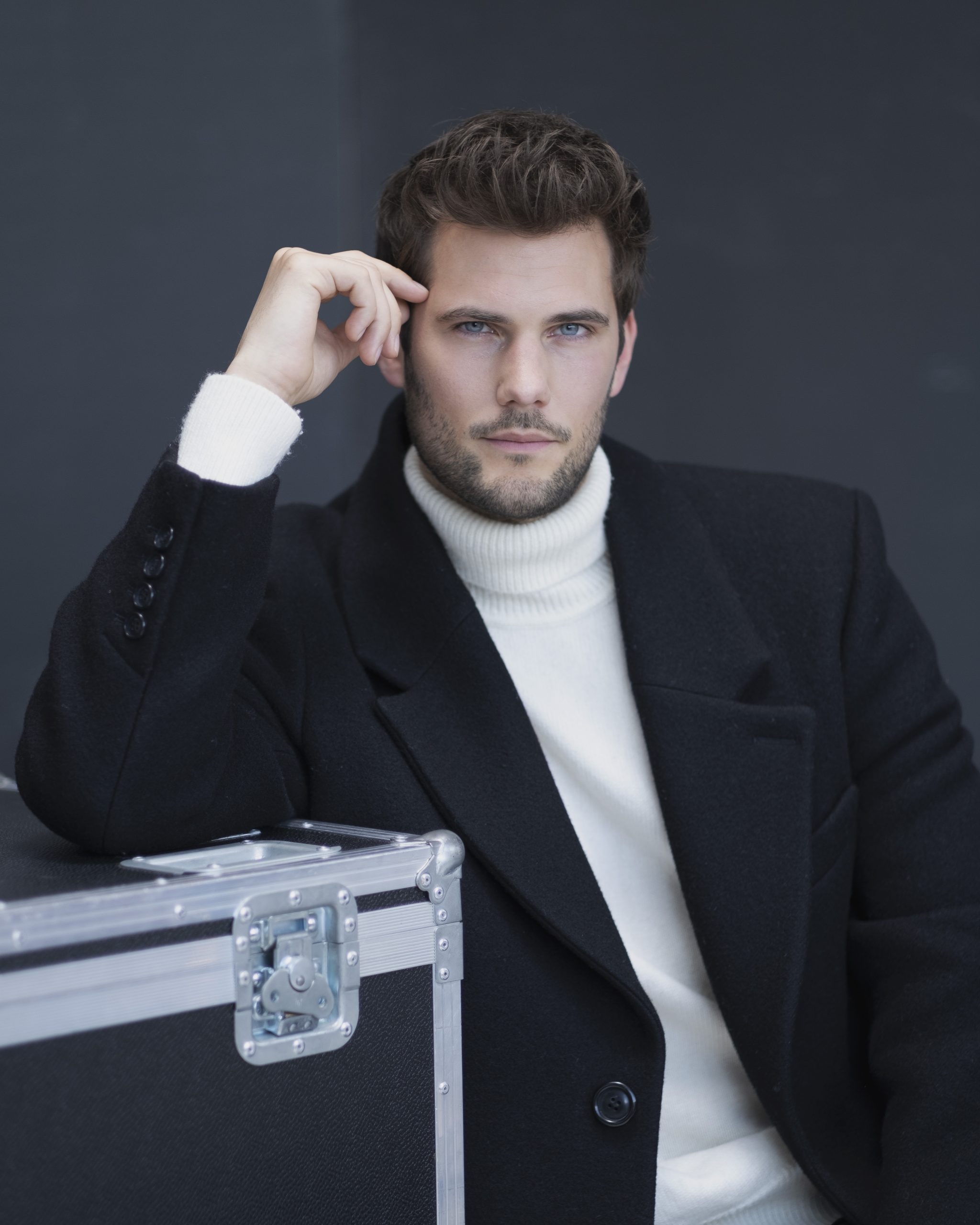 Junge Frau in weißem Kleid im Wald vor einer wehenden Leinwand oder Laken. Sie steht breitbeinig.